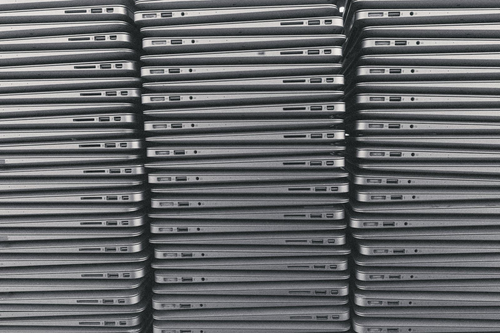 Closed laptops stacked in a tall column, seen edge on