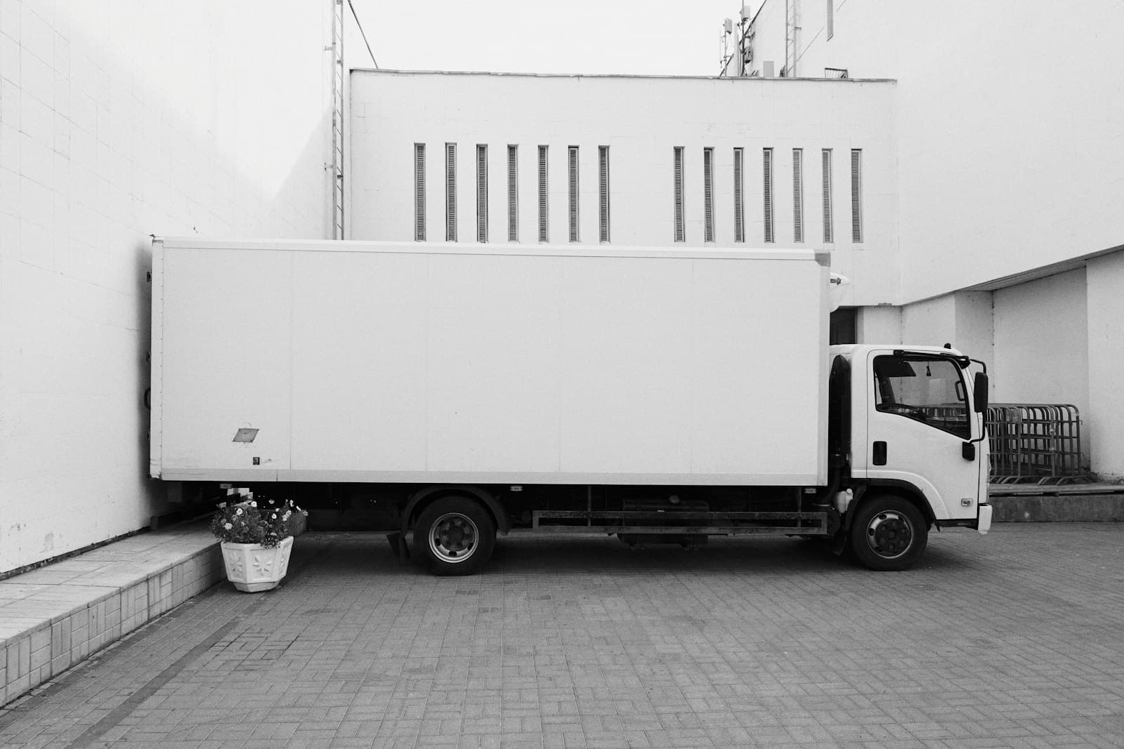 A plain white box truck parked against a building